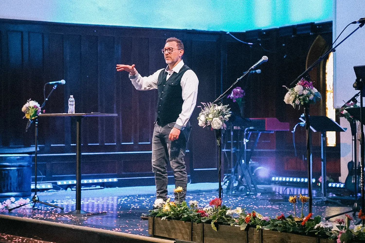 Bubba Jennings preaching on a stage lined with flowers