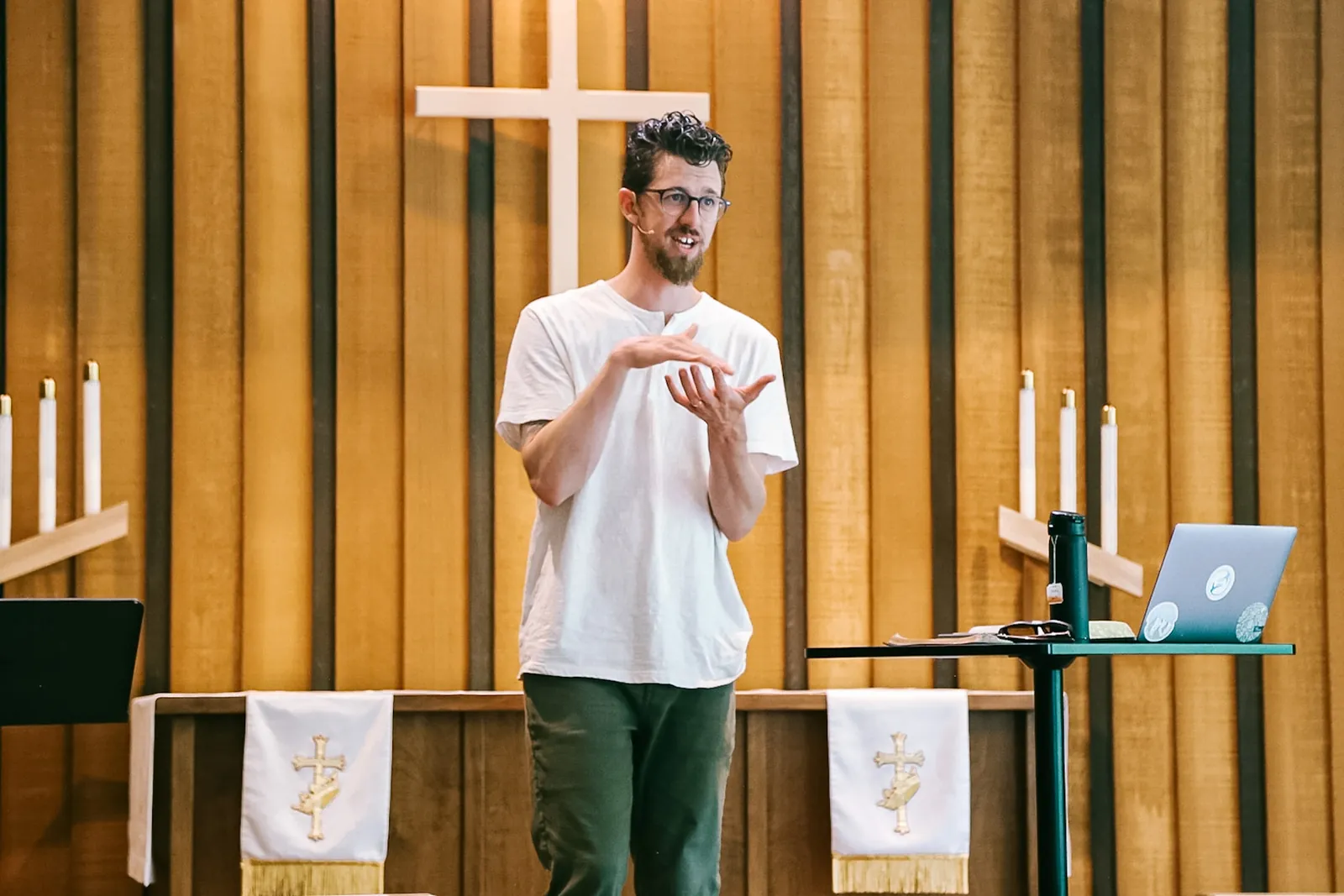 A pastor talking with his hands from a wooden pulpit
